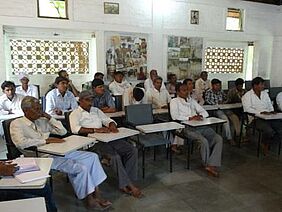 Men sitting at tables in a classroom.
