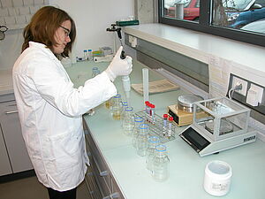 Wissenschaftlerin mit Pipette und verschiedenen Behältern.