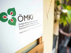 Panneau avec le logo de l’ÖMKi sur la façade d’un bâtiment.