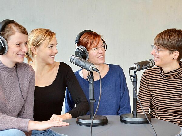 Vier Personen an einem Tisch an Mikrofonen