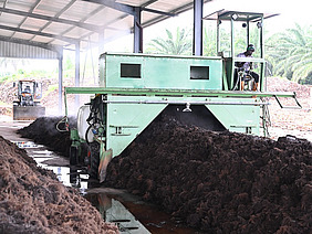 A man driving over compost with heavy machinery.