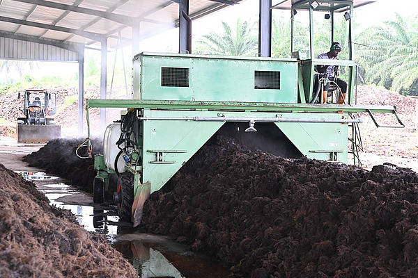 A man driving over compost with heavy machinery.