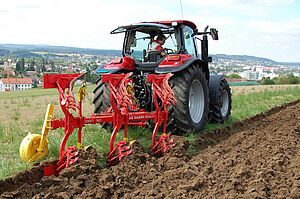 Ein Pflug, der von einem Traktor gezogen wird.