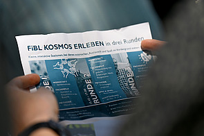 Programm wird von zwei Händen gehalten.