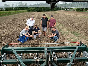 Forschende mit Landwirt auf dem Feld.