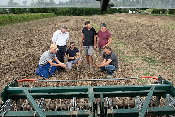 Forschende mit Landwirt auf dem Feld.