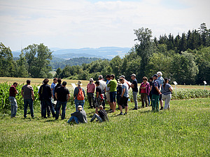 Gruppe von Personen auf dem Feld vor einer Ackerkultur.