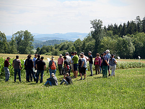 Groupe de personnes dans un champ devant une culture agricole.