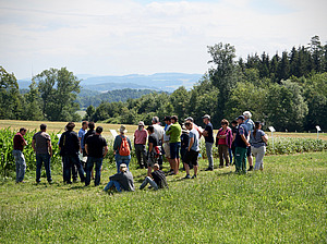 Group of people in the field in front of a crop.
