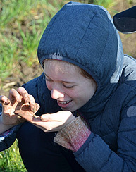 Junge Schülerin mit Regenwurm auf der Hand.