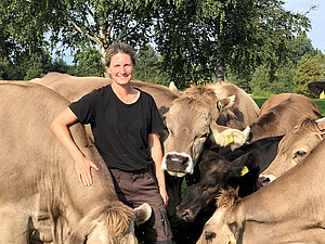 Auf dem Foto ist Marie Dittmann zu sehen, umgeben von einer Herde Wiederkäuer.
