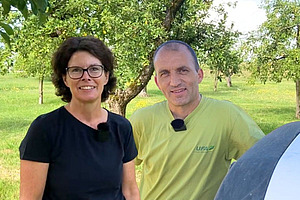 Porträt einer Frau und eines Mannes, welche auf einer Obstweide stehen.