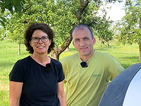 Porträt einer Frau und eines Mannes, welche auf einer Obstweide stehen.