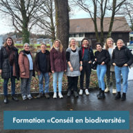 Eine Gruppe von ca 12 Menschen stet draussen auf einem Platz mit Bäumen im Hintergrund. Die Menschen tragen Winterkleidung und sind zwischen 30 und 50 Jahre alt. Sie lächeln in die Kamera.