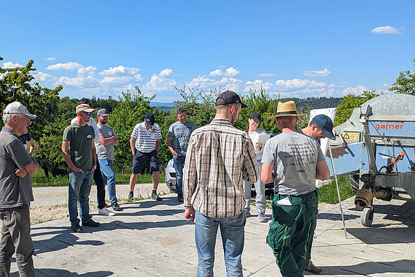 Mehrer Personen im Kreis, auf landwirtschaftlichem Betrieb.