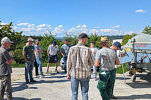 Mehrer Personen im Kreis, auf landwirtschaftlichem Betrieb.
