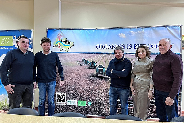 Five people in front of a poster.