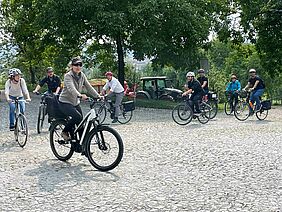 Mehrere Radfahrer*innen, die hintereinander fahren.