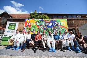 Andreas Sandhäger, Direktor des LLH; Karsten Schmal, Präsident Hessischer Bauernverband, Vize-Präsident des dt. Bauernverbandes; Dr. Alexander Gerber (Vorstand BÖLW, Moderation); Fenja Petersen, Leiterin Kommunikation Firma dennree, Goldsponsor; Priska Hinz, Landwirtschaftsministerin Hessen; Dr. Felix Prinz zu Löwenstein, Vorsitzender BÖLW; Carsten Veller, FiBL Deutschland, Projektleiter Öko-Feldtage; Prof. Dr. Gunter Backes, Fachgebietsleitung ökologische Pflanzenzüchtung und Agrarbiodiversität, Universität Kassel; Prof. Arno Ehresmann, Vize-Präsident der Universität Kassel; Dr. Uli Zerger, Geschäftsführer Stiftung Ökologie & Landbau; Prof. Dr. Jürgen Heß, Fachgebietsleiter Ökologischer Land- & Pflanzenbau, Universität Kassel; Bettina Gerber, Künstlerin vor dem fertigen Kunstwerk.