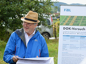 Ein Mann steht draussen vor einem Whiteboard und spricht.