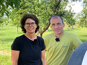 Eine Frau und ein Mann auf einer Wiese mit Bäumen.