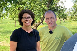 Eine Frau und ein Mann auf einer Wiese mit Bäumen.