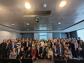 A room with around 40 people posing for a group photo.