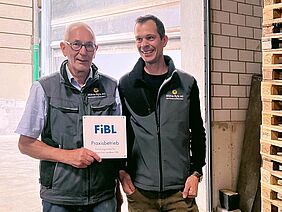 Deux hommes avec une plaquette du FiBL à la main