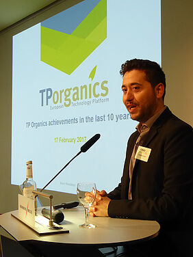 Man at a podium with a presentation in the background.