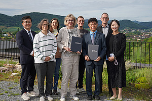 A group of people with a village and mountains in the background.