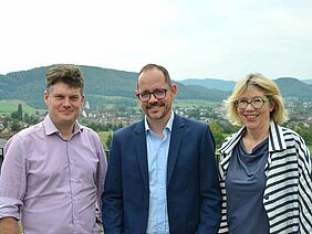 Two men and a woman looking into the camera.