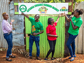 Four people pointing to a banner.