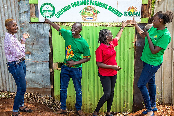 Four people pointing to a banner.