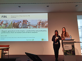 Two women give a lecture in front of a screen.