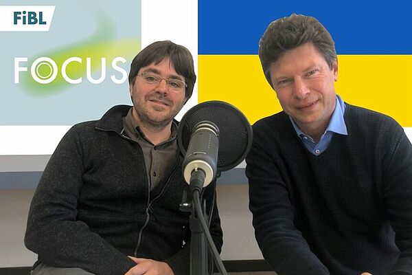 Tobias Eisenring und Toralf Richter hinter dem Mikrofon, dahinter das FiBL Podcast Logo und die Ukraine Flagge