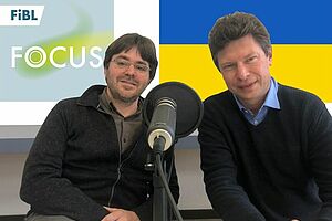 Tobias Eisenring und Toralf Richter hinter dem Mikrofon, dahinter das FiBL Podcast Logo und die Ukraine Flagge