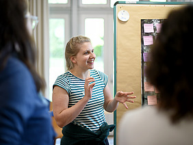 Junge Frau erklärt etwas anhand von Flipcharts.