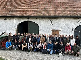 A group of people in front of a barn.