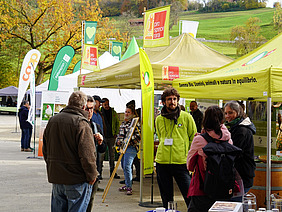 Zelte und Fahnen verschiedener Aussteller, Menschen im Gespräch.