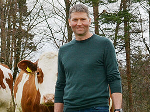Stefan Jegge in un prato con le vacche