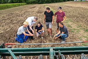 Landwirt und Forschende prüfen das Resultat der reduzierten Bodenbearbeitung