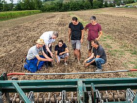 Landwirt und Forschende prüfen das Resultat der reduzierten Bodenbearbeitung