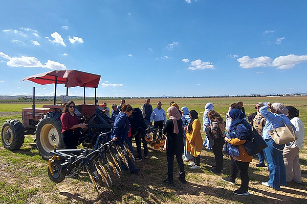 A tractor with an attached weeder on a field with spectators.