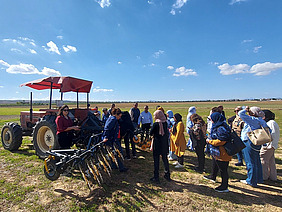A tractor with an attached weeder on a field with spectators.