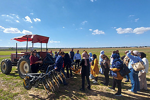 A tractor with an attached weeder on a field with spectators.