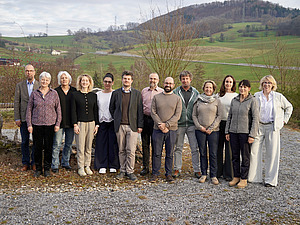 Un gruppo di persone con una collina verde sullo sfondo.