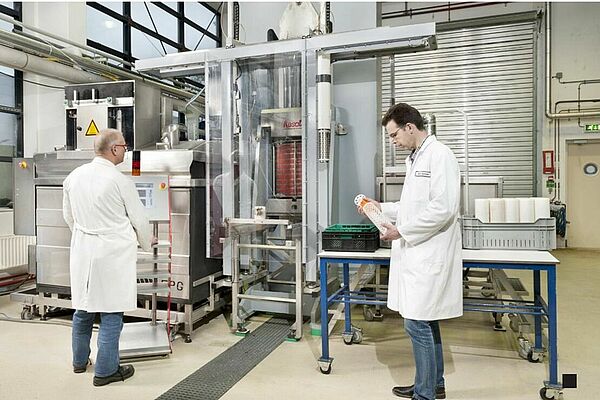 2 people stand in front of a high pressure machine