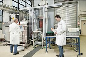 2 people stand in front of a high pressure machine