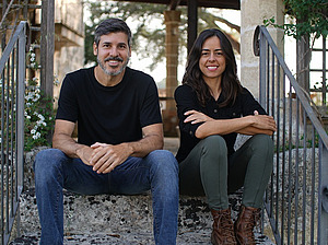 A man and a woman sitting on a flight of stairs outside.