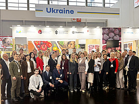 A group of around 40 people in front of a stand.